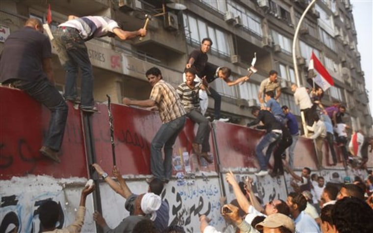 Some hundreds of Egyptian activists demolish a concrete wall built around a building housing the Israeli embassy in Cairo, Egypt, to protect it against demonstrators, as they raise their national Friday, Sept. 9, 2011. (AP Photo/Amr Nabil)